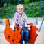 Dreng smiler på en Vippedyr – Bulldozer på en legeplads.