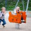 Børn leger på en orange Vippedyr – Bulldozer fjedergynge på legeplads
