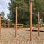 Trækstænger placeret i udendørs fitnessområde med grønne træer i baggrunden.