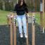 Kvinde balancerer på træbjælker i fitnesspark.