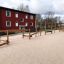 Robinia motorikbane installeret i sandet med balancebomme og reb nær røde bygninger