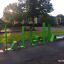 Grønne fitnessredskaber Ribbon Fitness II i en offentlig park ved solnedgang.