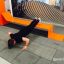 Mand laver push-ups på moderne orange Ribbon Fitness II udendørs fitnessudstyr.