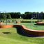 Multiarena Træ med kurve og bølget design i parkmiljø med aktive børn og voksne.
