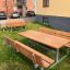 Picnic bænkebord af galvaniseret stål og lærketræ med tilpasning til kørestol, placeret udendørs.