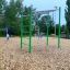 Monkey bars med ringer på legeplads med flisbelægning.
