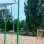 Monkey bars med ringe, stålstænger og grønne støttepæle på legeplads