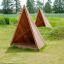 Tipi Natur træhytte til legeplads i grønt udendørs område.