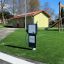 Legepanel – Tankstation på legeplads med grønt græs og legeredskaber i baggrunden.