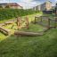 Robinia Balancerampe placeret i en grøn park med bygninger i baggrunden.