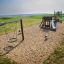 Robinie vippedyr - Skovvognen på en børnelegeplads med sand, gynger og rutsjebane nær stranden.