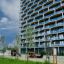 Klatrekiosken Natur - Legehus med rutsjebane og klatrevæg i træ på legeplads i moderne bymiljø.