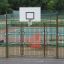 Udendørs basketbalbane med Tiger flettet hegn og hvid basketballkurv.