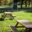 Bænkebord i lærk placeret i en park på en solrig dag