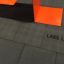 Grå Gummifliser 90 med Lars Laj logo nær orange legepladsudstyr.