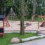 Legehuset Natur legeplads med rutsjebane og klatrestativ i en park.