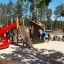 Børn leger på Mastodont legetårn med spiral rutsjebane på en legeplads i skoven.