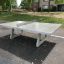 Fristående bordtennisbord af beton placeret udendørs i parkområde.