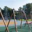 Sædegynge på legeplads i udendørs parkområde.