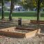 Sandkasse i lærketræ placeret i en park om efteråret.