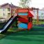 Legehus med rutsjebane og klatrevæg på legeplads