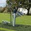 Udendørs fitnessudstyr med pedal- og håndtræner på grønt græs i park.