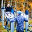 To mænd og en kvinde træner på udendørs fitnessudstyr i en park om efteråret.