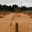 Legepladsudstyr Balancegang med klatrenet og balancebomme i en skovklædt park.