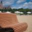 Sofa Wave udendørs bænk (lærk) placeret på sandstrand med udsigt til slot.