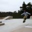 Teenager udfører tricks på skateboard i skateboardpark.