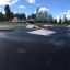 Corner skatepark med forskellige ramper og forhindringer på asfalteret område