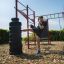 Mand træner ben ved at sparke dæk på udendørs fitnessudstyr New Age Fit.