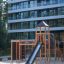 Explorer - Legetårne med rutsjebane og klatrestativ på legeplads med sandbund.