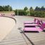 Rosa lounge sofa på trædæk i udendørs park omgivelser.