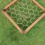 Hexagonal klatrevæg af træ i græsplæne.