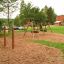 Kolbøtttestang triple på legeplads med træbark og grønne træer i baggrunden.