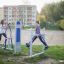 To unge piger bruger Air Walker udendørs fitnessudstyr på en offentlig park.